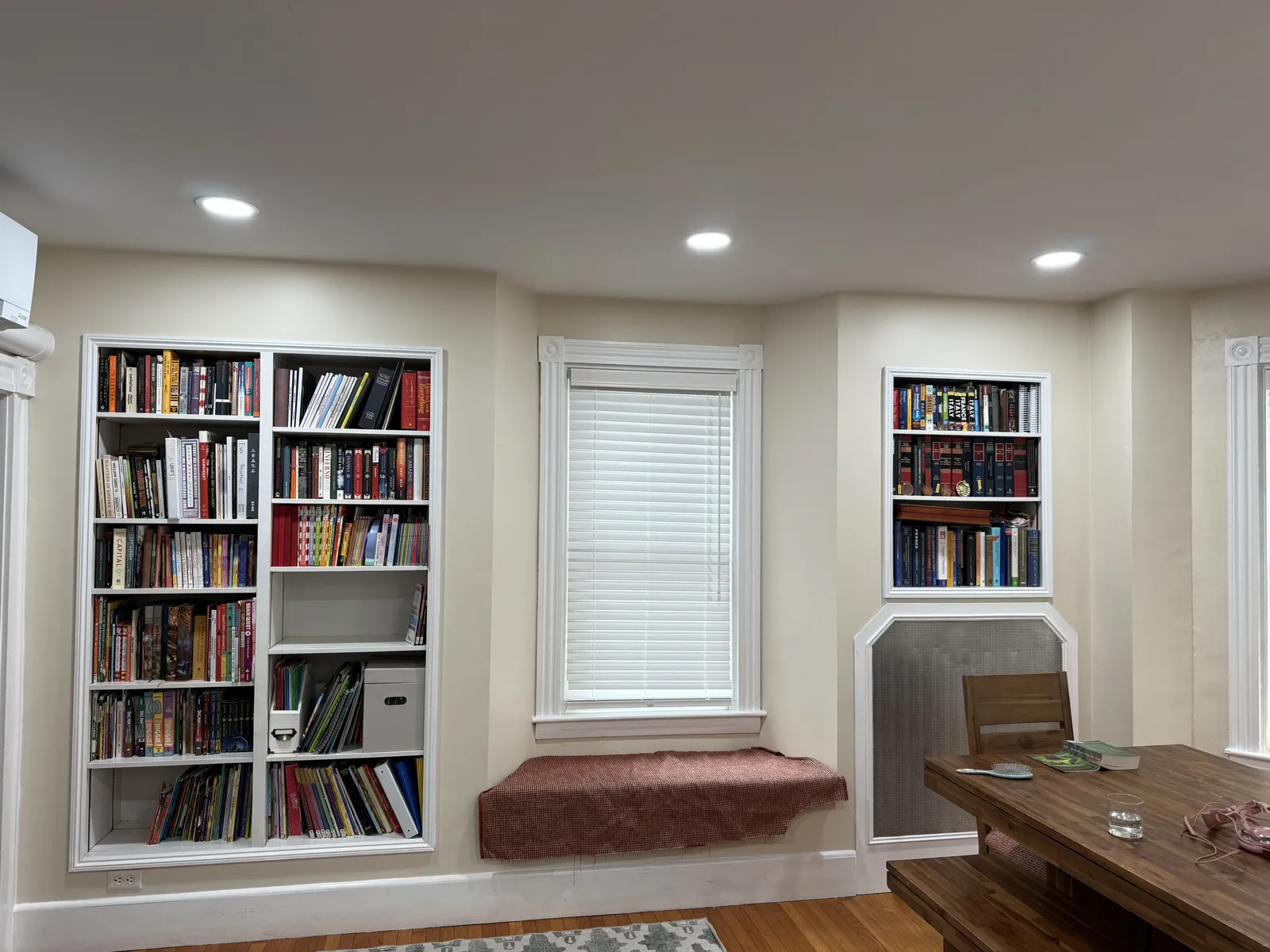 Living room with new recessed lighting over built-in bookshelves and a window seat